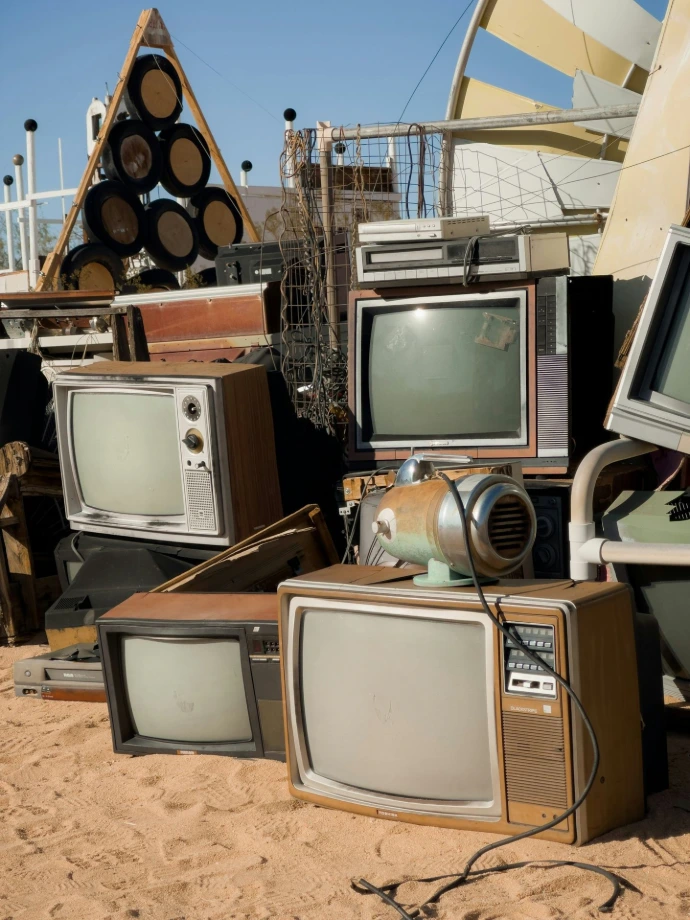 a pile of old tvs sitting on top of a sandy beach